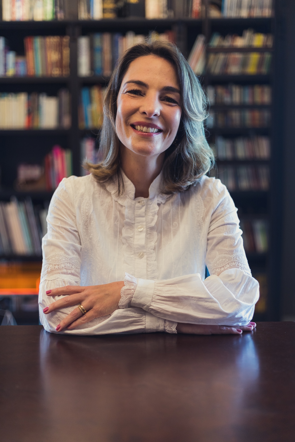 Nutricionista Martha Amodio sorrindo diante de uma estante de livros